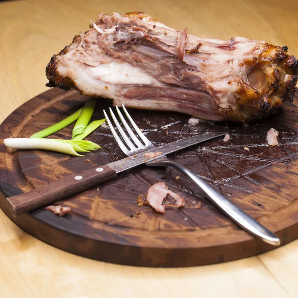 Pork bone with knife and fork, leftovers on a table after big di — Stock Photo, Image