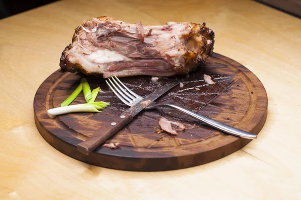 Osso de porco com faca e garfo, sobras em uma mesa depois do grande di — Fotografia de Stock