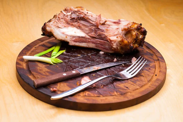 Carne di maiale con coltello e forchetta, avanzi su un tavolo dopo big di — Foto Stock