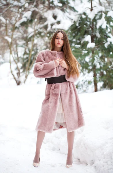 冬の公園でポーズの毛皮のコートで若い美しいブルネットの女性 — ストック写真