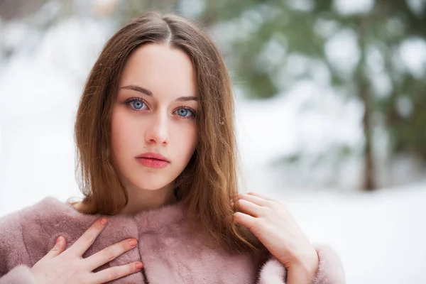 Young beautiful brunette woman in fur coat posing on winter park — Stock Photo, Image