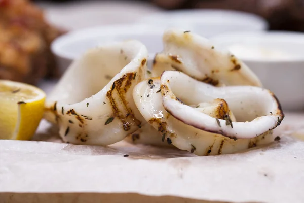 Grilled squid rings on a wooden board with sauce — Stock Photo, Image