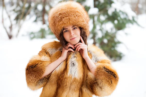 Jeune belle fille dans un chapeau de fourrure et un manteau de fourrure de renard rouge — Photo