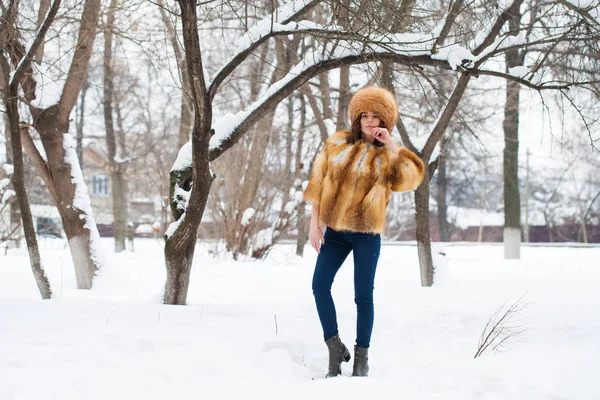 Young beautiful girl in a fur hat and a red fox fur coat — Stock Photo, Image