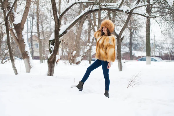 Young beautiful girl in a fur hat and a red fox fur coat — Stock Photo, Image