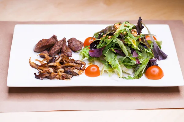Салат с рукколой и жареными грибами и печенью — стоковое фото