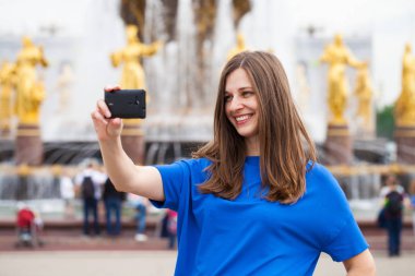 Gülümseyen kadın almak bir fotoğrafını bir akıllı telefon ile. Selfi