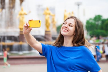 Gülümseyen kadın almak bir fotoğrafını bir akıllı telefon ile. Selfi