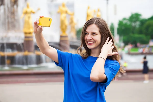 Mujer sonriente tomar una foto de sí misma con un teléfono inteligente. Selfi. —  Fotos de Stock