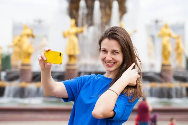 Улыбающаяся женщина фотографирует себя со смартфоном. Селфи — стоковое фото