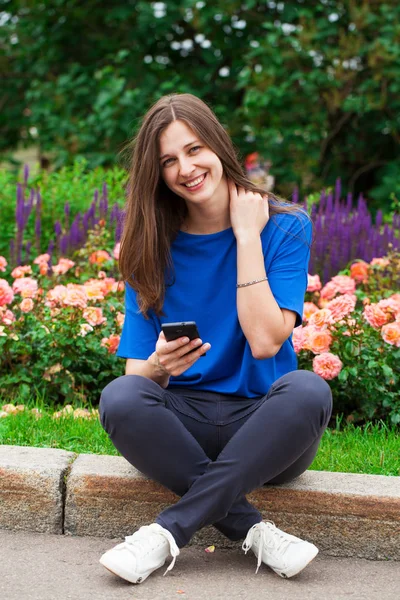 Junge brünette Frau liest eine Nachricht am Telefon — Stockfoto