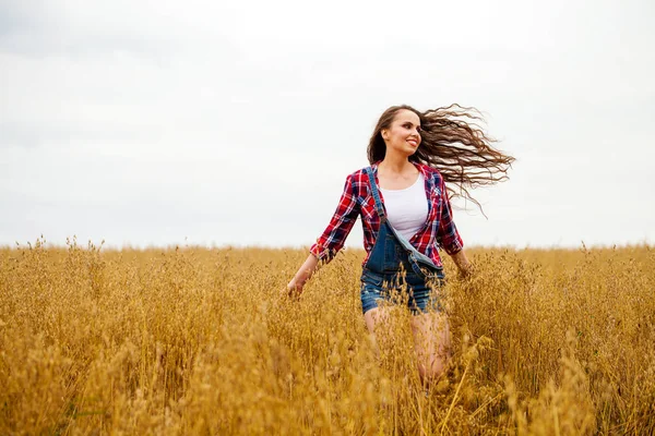 Junge schöne Frau, die in einem Feld spaziert, Sommer im Freien — Stockfoto