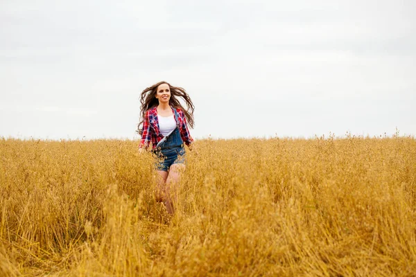 Ung vacker kvinna promenader i ett fält, sommar utomhus — Stockfoto