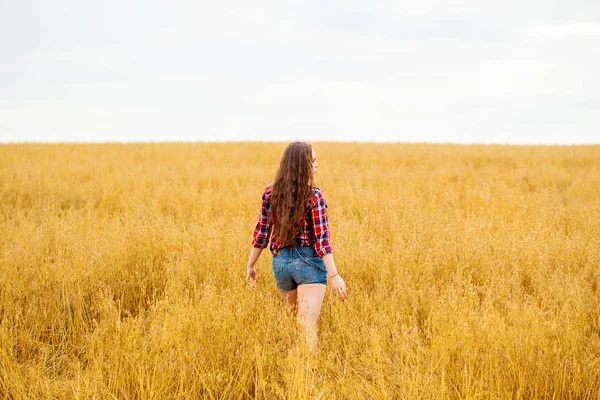 Junge schöne Frau, die in einem Feld spaziert, Sommer im Freien — Stockfoto