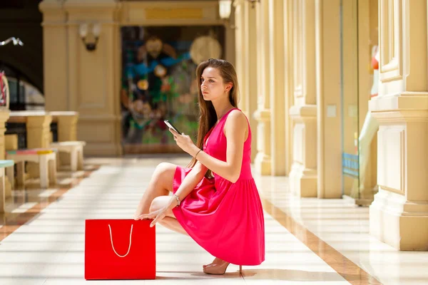 Mujer morena joven con algunas bolsas de compras en el centro comercial — Foto de Stock