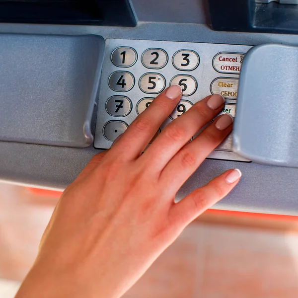 Close up of hand entering pin at an ATM. Finger about to press a