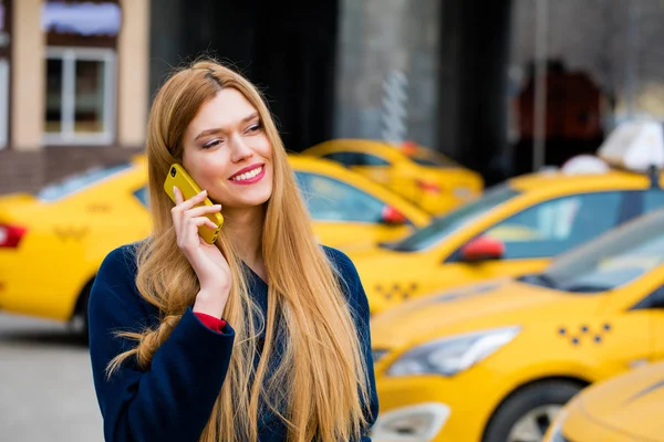 Een jong meisje roept een taxi via de telefoon. — Stockfoto