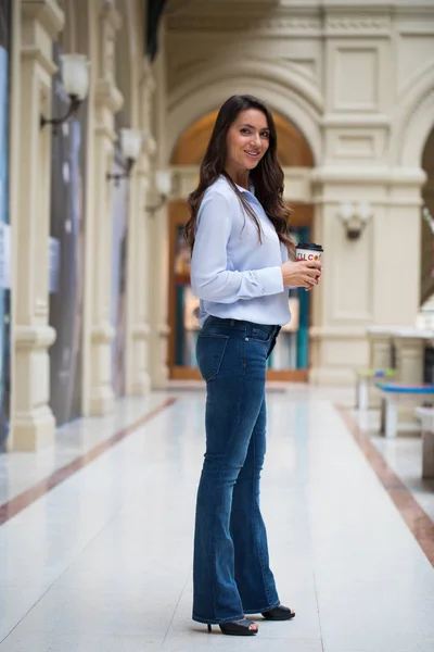 Ung vacker brunett kvinna i blå jeans och blus promenader — Stockfoto