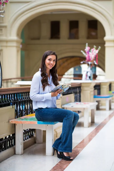 Joven morena haciendo notas en un cuaderno sentado en la m — Foto de Stock