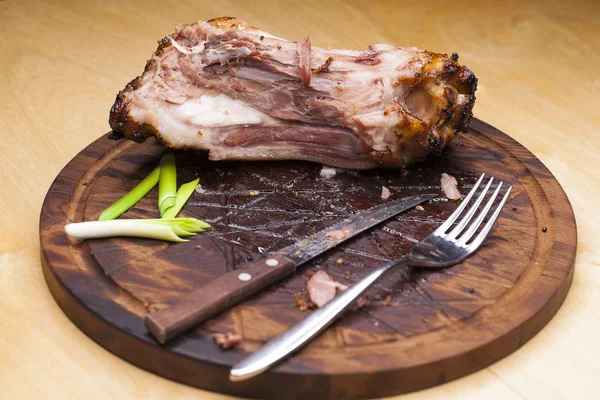 Свиная кость с ножом и вилкой, остатки на столе после большой ди — стоковое фото