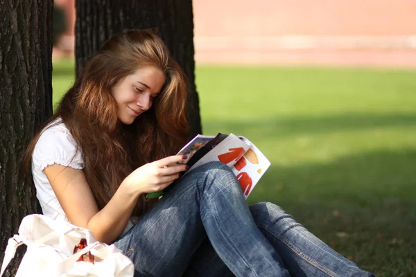 Joven hermosa mujer morena leyendo una revista de mujeres en el —  Fotos de Stock