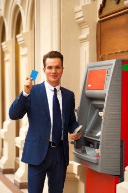 Bir Atm içinde bir alışveriş merkezi yakınındaki bir genç işadamı duran