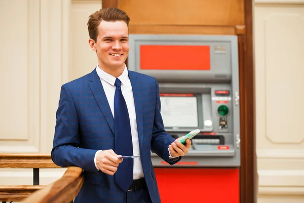 Молодий підприємець стоїть біля банкомату у торгівельному центрі — стокове фото