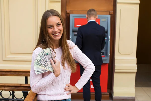 Unga blonda kvinnan håller en kontant dollar — Stockfoto