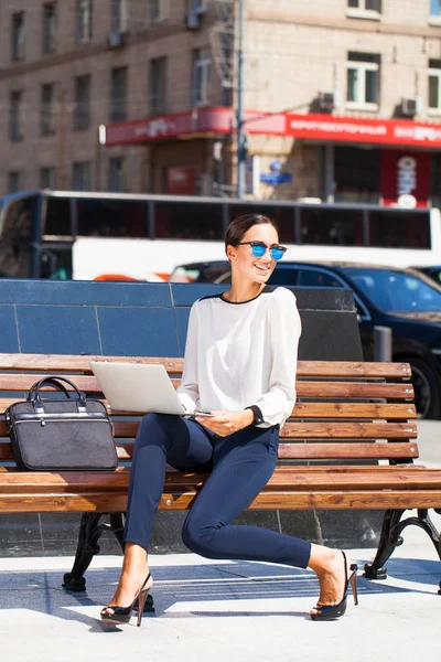 Jonge mooie zakenvrouw werkt op laptop, zomer straat — Stockfoto