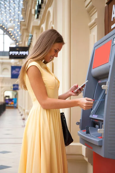 Heureuse femme blonde retirant de l'argent de la carte de crédit au distributeur automatique — Photo