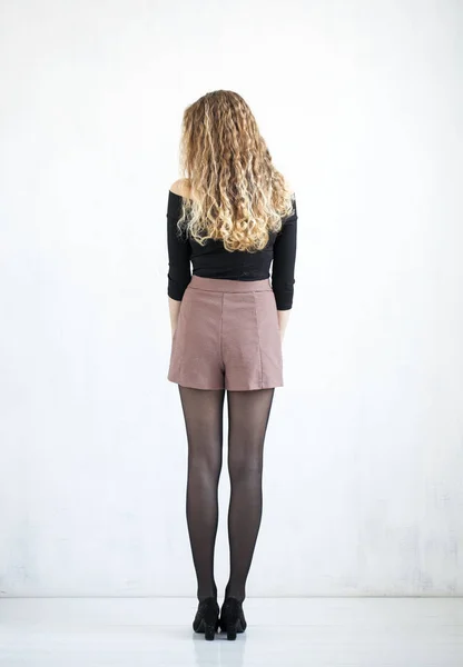 Portrait of full length curly blonde in a black blouse and short — Stock Photo, Image