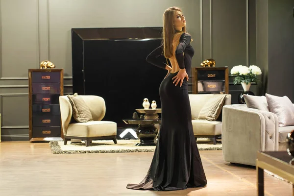 Σέξι ξανθιά γυναίκα με μαύρο βραδινό φόρεμα που ποζάρει σε έπιπλα — Φωτογραφία Αρχείου
