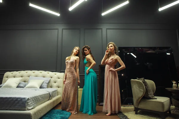 Τρεις νεαρές γυναίκες με βραδινά φορέματα ποζάρουν σε ακριβό εσωτερικό — Φωτογραφία Αρχείου