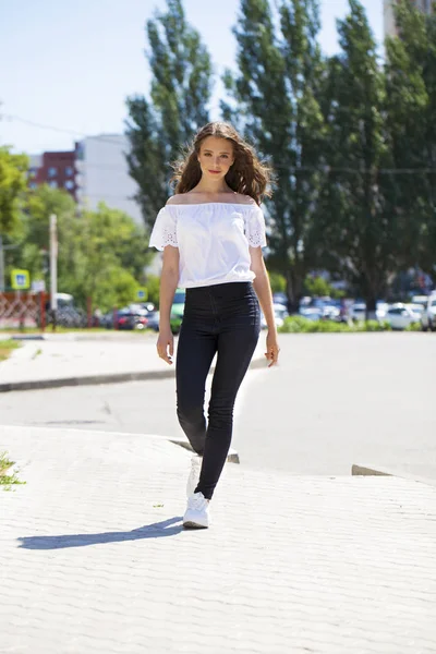 Kot pantolon ve beyaz bluz yürüyüş genç güzel esmer kadın — Stok fotoğraf