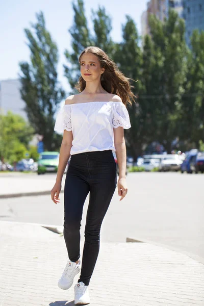 Jovem bela mulher morena em jeans e blusa branca andando — Fotografia de Stock