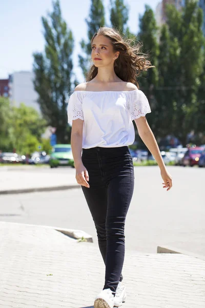 Jovem bela mulher morena em jeans e blusa branca andando — Fotografia de Stock