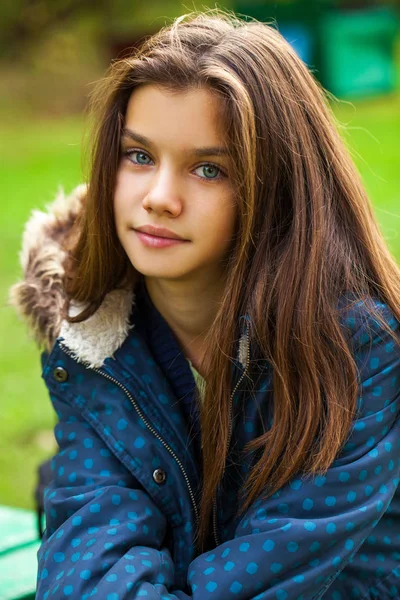 Όμορφη μελαχρινή μικρό κορίτσι που ποζάρει στο φθινόπωρο πάρκο στο παρασκήνιο — Φωτογραφία Αρχείου