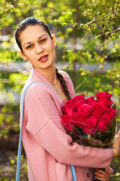 Jong gelukkig brunette vrouw met een boeket van rode rozen — Stockfoto