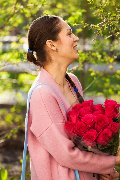 Jong gelukkig brunette vrouw met een boeket van rode rozen — Stockfoto