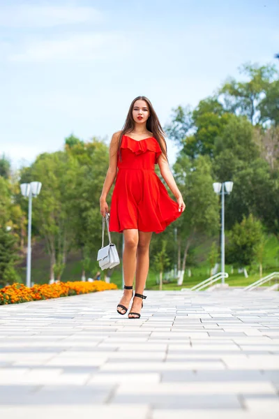 Jovem modelo bonito em vestido vermelho andando na rua de verão — Fotografia de Stock