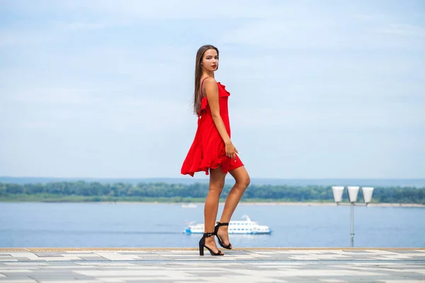 Joven modelo hermosa en vestido rojo caminando en la calle de verano — Foto de Stock