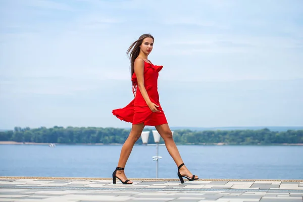 Jeune beau mannequin en robe rouge marchant dans la rue d'été — Photo