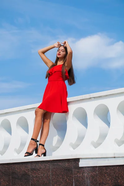 Молодая красивая женщина в красном платье на летней улице — стоковое фото