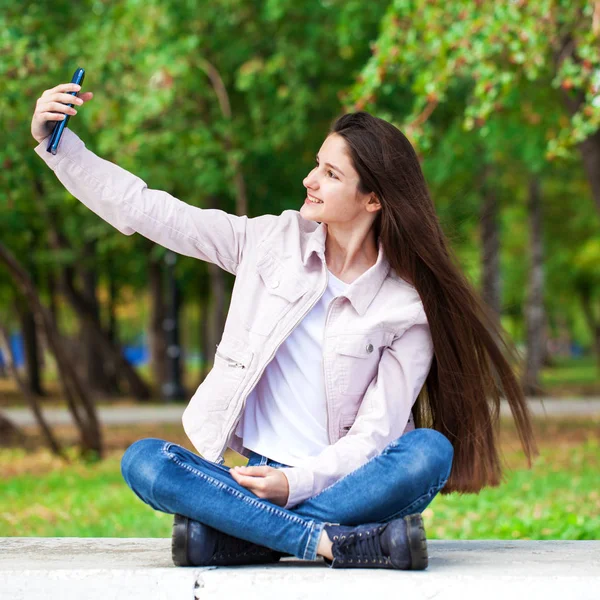 Esmer kız otururken bir cep telefonu kendini fotoğraflar — Stok fotoğraf