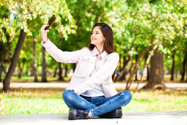 Brunette fille se photographie sur un téléphone portable tout en étant assis — Photo