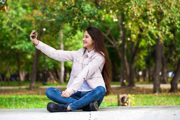 Morena menina fotografa-se em um telefone celular enquanto sentado — Fotografia de Stock
