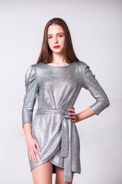 Gümüş renkli elbisesi olan genç ve güzel bir manken. 