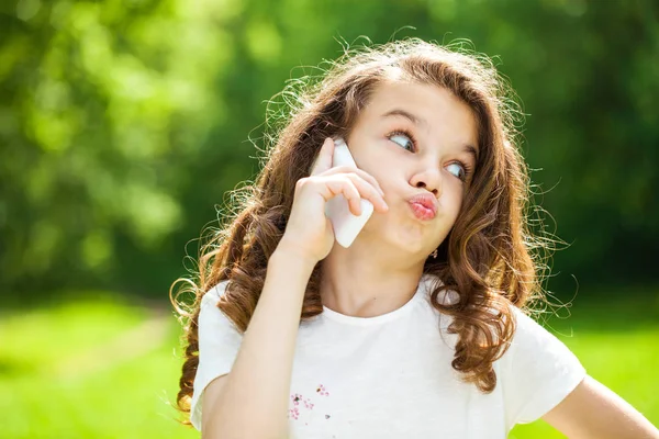Porträtt av en vacker ung liten flicka ringer via telefon — Stockfoto