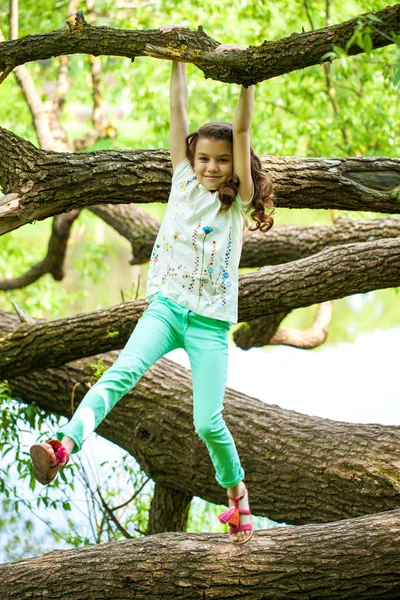Glad liten flicka på trädstammen — Stockfoto