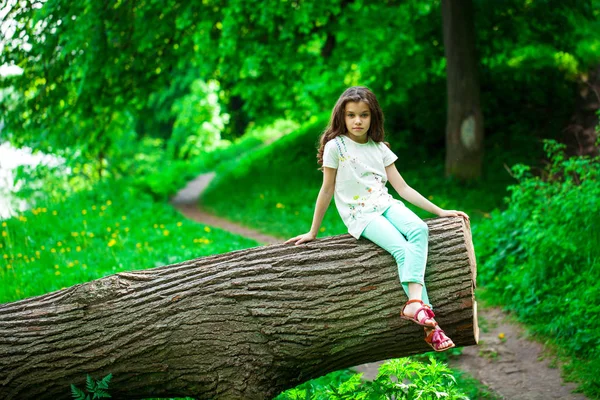 Petite fille sur tronc d'arbre — Photo